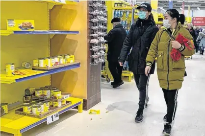  ?? JOHN MAHONEY/POSTMEDIA NEWS ?? Shoppers wearing masks walk by depleted shelves at the Maxi store in Pointe-Claire on March 13.