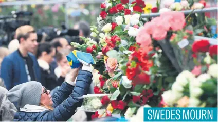  ?? AFP ?? A woman lays a Swedish flag at a makeshift memorial near the site where a truck slammed into a crowd outside a busy department store in central Stockholm.Picture: