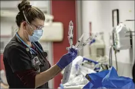  ?? I rfan Khan Los Angeles Times ?? JENNIFER CASPARY, an emergency room in- charge nurse at Desert Valley Hospital in Victorvill­e, attends to a COVID- 19 patient Thursday.