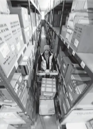  ?? Alastair Grant / Associated Press ?? Lovespace storage warehouse worker Piotr Waligora stocks goods at the warehouse in Dunstable, England. Lovespace says business is booming as companies stockpile goods.