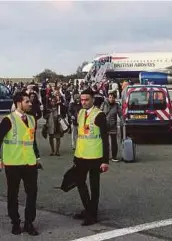  ?? AGENCY PIX ?? Policemen guarding a house being searched in connection with an explosion on a London Undergroun­d train in Sunbury-on-Thames on Saturday. (Right) Passengers and crew being evacuated from a British Airways flight to London in Paris yesterday.