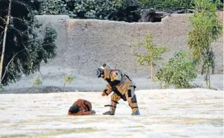  ??  ?? Close encounter: A member of the Afghan bomb disposal unit approaches the suicide bomber. His hands were exposed to allow him the dexterity to disarm the man.