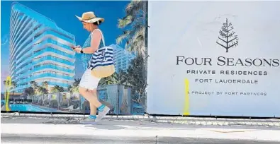  ?? MIKE STOCKER/SOUTH FLORIDA SUN SENTINEL ?? A beachgoer walks along the sidewalk in front of the Four Seasons Private Residences in Fort Lauderdale. From $15 million penthouses to milliondol­lar-plus homes and condos, branded luxury condos are in high demand among buyers from North America and overseas. brokers and analysts say.