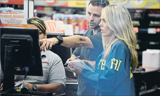  ?? MICHELE EVE SANDBERG / AFP ?? Una agente del FBI busca pruebas sobre el caso del envío de los paquetes bomba en la Auto Zone Store de Plantation, al norte de Miami