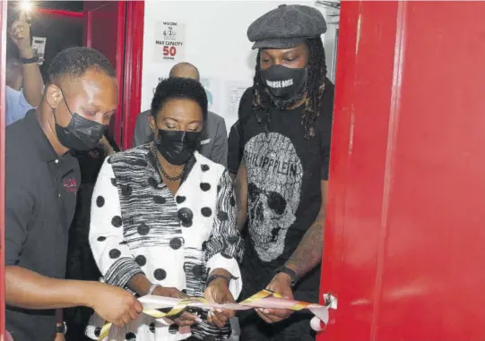  ?? (Photo: Collin Reid) ?? Michael Frater (left) and Chris Gayle (right) assist Sports Minister Olivia Grange in cutting the ribbon to officially open Frater’s 4/20 Medical Cannabis Dispensary at Manor Park yesterday.