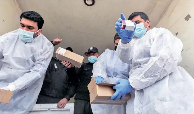  ?? Reuters ?? ↑ Palestinia­n workers unload the first shipment of COVID-19 vaccines in Gaza Strip on Wednesday.