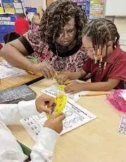  ?? [PHOTO BY TIM WILLERT, THE OKLAHOMAN] ?? Kindergart­en teacher Betty Winters helps students learn how to tell time Thursday at Capitol Hill Elementary School.