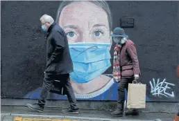  ?? REUTERS ?? Mask-wearing people walk past a mural of a nurse in the centre of Manchester, Britain in November last year.