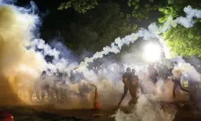  ?? Samuel Corum, AFP via Getty Images ?? Tear gas rises above as protesters face off with police during a May 31 demonstrat­ion outside the White House over the death of George Floyd.