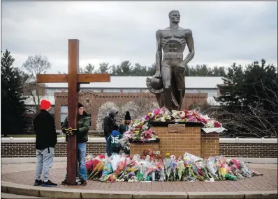  ?? ?? Dan Beazley of Northville Township holds a large wooden cross Wednesday as a crowd gathers at the Spartan Statue, where a makeshift memorial continues to build with flowers and keepsakes, at Michigan State University in East Lansing, Mich.
(File Photo/ap/the Flint Journal/jake May)