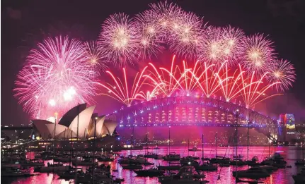  ?? Mick Tsikas / EPA, Suhaib Salem / Reuters, Ahn Young-joon / AP Photo ?? New Year’s Eve fireworks illuminate Sydney Harbour with its Opera House and bridge. Palestinia­n artist Yazed Abu Jarad holds his national flag after making a sand sculpture that reads ‘Welcome 2017’ on a beach in the northern Gaza Strip. A woman prays...