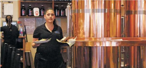  ?? LUIS SÁNCHEZ SATURNO/THE NEW MEXICAN ?? Ana Chavez, a waitress at Blue Corn Café & Brewery, delivers food Monday to a customer. Originally from El Salvador, but now a U.S. citizen, she worries about her brother, Oscar, who has been allowed to live and work in the United States under a...