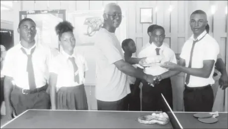  ??  ?? Jocelyn Morian (centre) presenting table tennis equipment to students of Kwakwani secondary