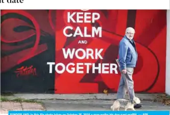  ??  ?? SUNDERLAND: In this file photo taken on October 25, 2016 a man walks his dog past graffiti. — AFP