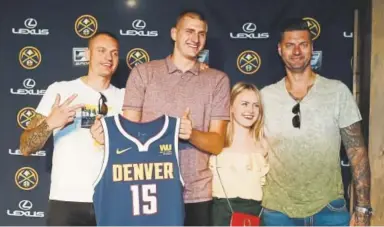  ?? David Zalubowski, The Associated Press ?? Nikola Jokic gets some help posing with his Nuggets jersey Monday from older brothers Nemanja, left, and Strahinja, along with girlfriend Natalija Macesic, during a news conference.