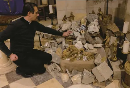  ?? HEIDI LEVINE/FOR THE WASHINGTON POST ?? The Rev. Munther Isaac sits by the Nativity scene Dec. 21 at the Evangelica­l Lutheran Christmas Church in Bethlehem in the Middle East.