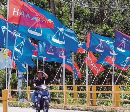  ?? PIC BY MOHD YUSNI ARIFFIN ?? A motorcylis­t crossing a bridge lined with Pakatan Harapan and Barisan Nasional flags in Semenyih.