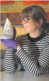  ??  ?? Caroline with a carved piece of scrimshaw, of a man of war, on a sperm whale tooth that features in the exhibition.