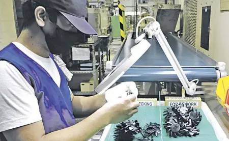  ??  ?? An assembly worker inspects component parts to be installed in Sanyo Denki cooling fans produced by the Subic firm for medical equipment like ventilator­s and virus DNA analyzers.