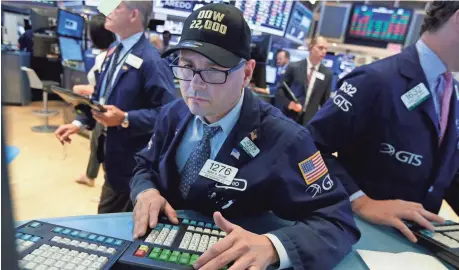  ?? RICHARD DREW, AP ?? Specialist Mario Picone wears a “Dow 22,000” hat as he works on the floor of the New York Stock Exchange on Wednesday. The Dow has gained 11.4% this year and is up 236% since its bear market low of 6547.05.