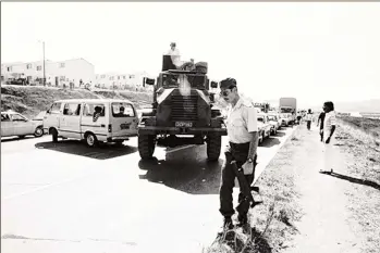  ??  ?? A South African policeman escorts a police Casspir towards the entrance of Phoenix, near Durban, in September 1985.