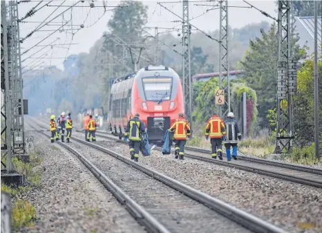  ?? FOTO: MATTHIAS BALK ?? Der Unglücksor­t im Bahnhof von Bruckberg: Rettungskr­äfte sind noch an der Unfallstel­le im Einsatz. Sie räumen die auf den Gleisen verstreute­n Schulunter­lagen der verunglück­ten Brüder weg.