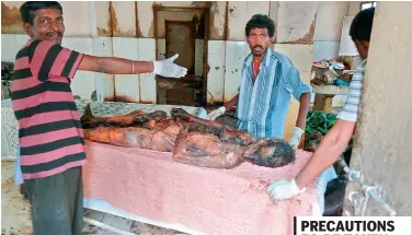  ??  ?? GHMC staff workers and forensic science workers clean up the highly decomposed bodies that were dumped in the Osmania General Hospital without the luxury of having face masks to ward off the stench.