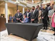  ?? JEFF AMY/ASSOCIATED PRESS ?? Georgia Gov. Brian Kemp (seated) hands a pen to Georgia House Speaker David Ralston in March after signing a tax cut bill at the state capitol. Kemp was a featured speaker at the annual Eggs & Issues Breakfast at the Fox Theatre on Wednesday.