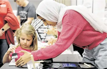  ?? Photos by Elizabeth Conley / Staff photograph­er ?? Zaynab Bashir, 14, of Friendswoo­d helps Kharra Hayes, 4, of Webster paint a tile during a “Know Your Muslim Neighbor” event at the Harris County Public Library Freeman branch. The community event was started by Muslim women in the area.