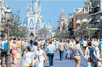  ?? ORLANDO SENTINEL FILE ?? Visitors fill Main Street, U.S.A., after a parade. Walt Disney World opened on a Friday, when children were still in school, meaning adults made up the majority of the 10,422 first-day visitors. On Saturday, the Magic Kingdom’s second day, attendance rose to 11,115.