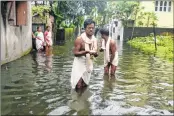  ??  ?? Residents wade through a flooded street as they perform funeral rituals during heavy showers in Siliguri on Sunday. —AFP