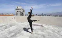 ??  ?? Sherazade Mami, a 28-year-old Tunisian profession­al dancer and performer at the Caracalla dance theatre and a teacher at the Caracalla dance school, practices while wearing a surgical mask on the roof of her apartment building.