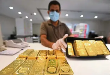  ?? – AFP ?? Gold rallies: A file picture showing a jeweller showcasing bars of gold at a shop in Dubai. The price of the metal touched a seven-year high of US$1,751.69 an ounce last Friday.some believe it has much further to go.