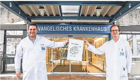  ?? FOTO: LARS FRÖHLICH ?? Rechts und links Abstand, in der Mitte das Zertifikat fürs Darmzentru­m: Prof. Daniel Vallböhmer (links) und Edmund Purucker vor dem Evangelisc­hen Krankenhau­s in Dinslaken.