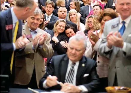  ?? THE ASSOCIATED PRESS ?? Janea Cox, back left, is embraced by Sarah Caruso as Georgia Gov. Nathan Deal signs a medical marijuana bill during a ceremony at the Statehouse, Thursday in Atlanta. The measure is also known as "Haleigh's Hope Act" after Cox's 5-year-old daughter,...