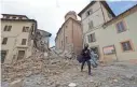  ?? ALESSANDRA TARANTINO/AP ?? A resident carrying his belongings walks through rubble Thursday after an earthquake destroyed part of Camerino, Italy.