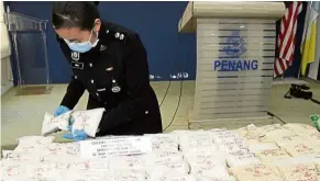  ??  ?? Catch of the day: a policewoma­n arranging the seized drugs for a press conference at the state police headquarte­rs in penang road.