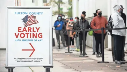  ?? JESSICA MCGOWAN/GETTY IMAGES ?? Georgians line up to vote in Atlanta in December’s Senate runoff election.