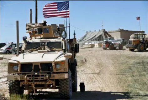  ?? HUSSEIN MALLA, FILE - THE ASSOCIATED PRESS ?? In this April 4, 2018 file photo, a U.S. soldier, left, sits on an armored vehicle behind a sand barrier at a newly installed position near the front line between the U.S-backed Syrian Manbij Military Council and the Turkish-backed fighters, in Manbij, north Syria. The U.S. military said Friday it has started pulling equipment, but not troops, out of Syria as a first step in meeting President Donald Trump’s demand for a complete military withdrawal.