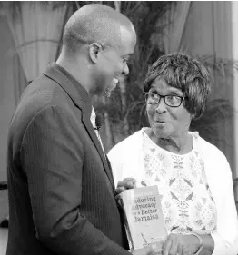  ??  ?? Rev’d Dr Devon Dick gives a copy of his latest book, ‘Enduring Advocacy for a Better Jamaica’, to his mother, Cynthia Dick, at the official book launch on Sunday, October 6, 2019, at the Boulevard Baptist Church in Kingston.