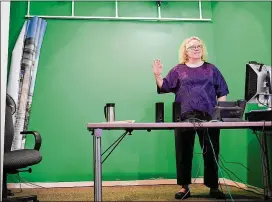  ?? KATHERINE FREY / WASHINGTON POST ?? Smithsonia­n educator Peg Koetsch stands in front of a green screen she uses to teach photograph­y to middle-schoolers on a U.S. base in Guam.