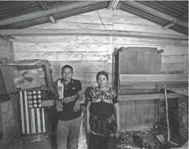  ?? ?? Catarina Tambriz Tambriz and her husband, Francisco Tzaj Quemá, stand in a sparse room that once belonged to their son but now holds corn. Diego Tzaj Ixtos painted the U.S. flag on a cabinet when he was 17, hoping to one day live and work in the U.S.