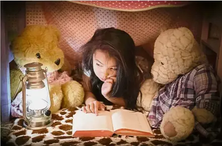  ?? — AFP ?? A little girl is reading a book to her teddy bears.