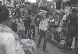  ?? MUMBAI
-AP ?? Workers carry boxes past roadside stalls in Mumbai.