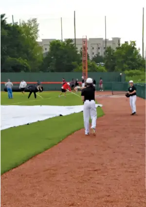  ?? Staff photo by Josh Richert ?? ■ A pair of Texas High baseball players play catch and workers squeegee the outfield while waiting out a weather delay Friday prior to Game 2 of the Tigers’ 5A bi-district series against Lucas Lovejoy at Tiger Field.