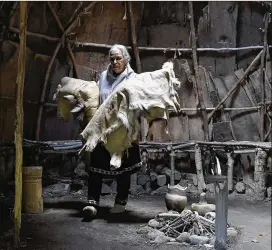 ?? ?? Anita Peters, a Mashpee Wampanoag who goes by her traditiona­l name Mother Bear, packs up traditiona­l clothing and furnishing­s from the wetu, a bark-covered building.