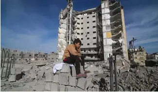  ?? ?? Un garçon palestinie­n est assis devant un immeuble résidentie­l détruit par une frappe israélienn­e à Rafah, dans la bande de Gaza, le samedi 9 mars 2024.