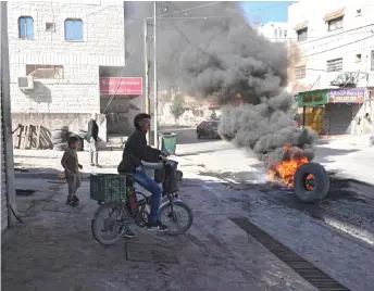  ?? — AFP photo ?? Burning tires block the entrance of the Palestinia­n village of Burqin, west of Jenin, in the Israeli occupied West Bank.