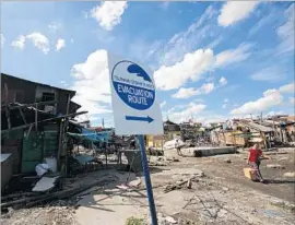  ?? Francis R. Malasig EPA ?? A WOMAN walks past a tsunami evacuation sign south of Manila. A U.S. congressio­nal panel voted to continue funding a global tsunami detection system.
