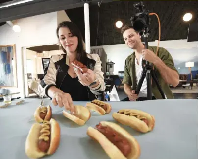  ?? STAFF PHOTOS BY MATT HAMILTON ?? Emily and Corey Critser work on a photo shoot at Lanewood Studio. At top, Emily uses an icing piping bag to precisely place ketchup and mustard on hot dogs.